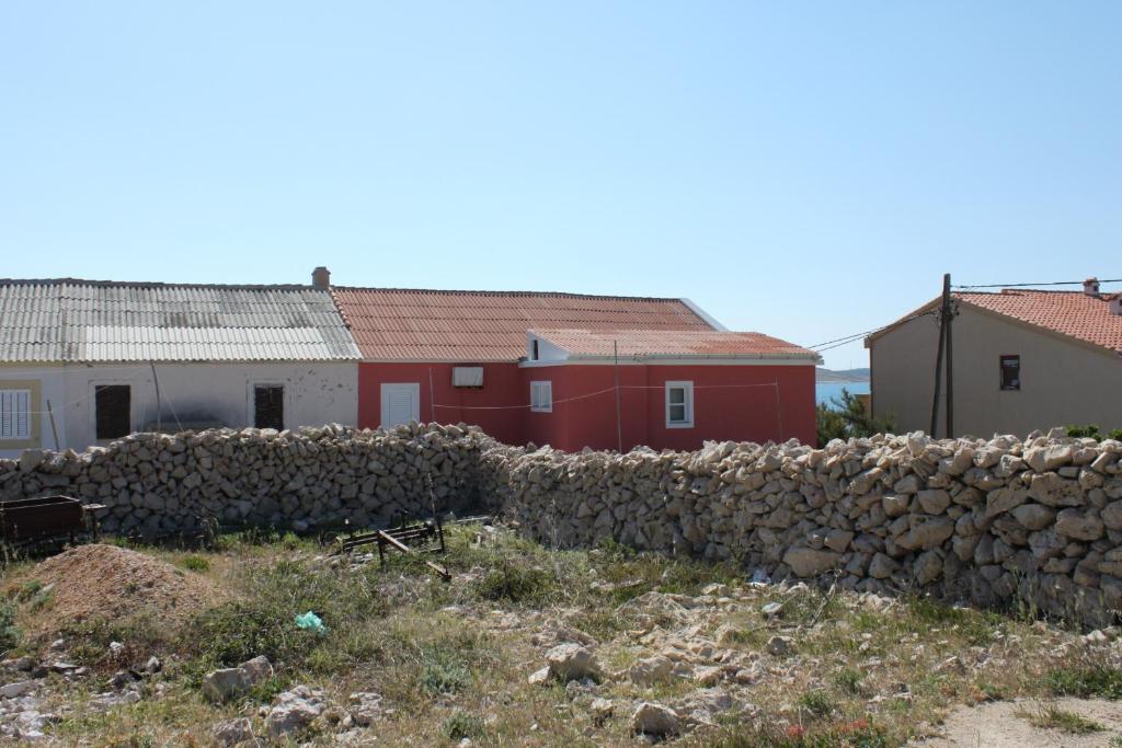 eine Steinmauer neben einem Gebäude und Häusern in der Unterkunft Rooms by the sea Kustici, Pag - 6288 in Kustići