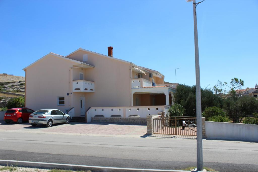 a white house on the side of a street at Apartments with a parking space Kustici, Pag - 6287 in Kustići