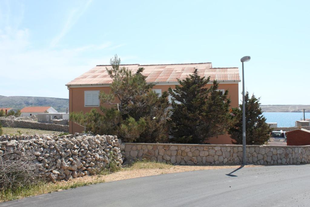 a house with a stone wall and a street light at Apartments with parking space Kustici, Pag - 6287 in Kustići