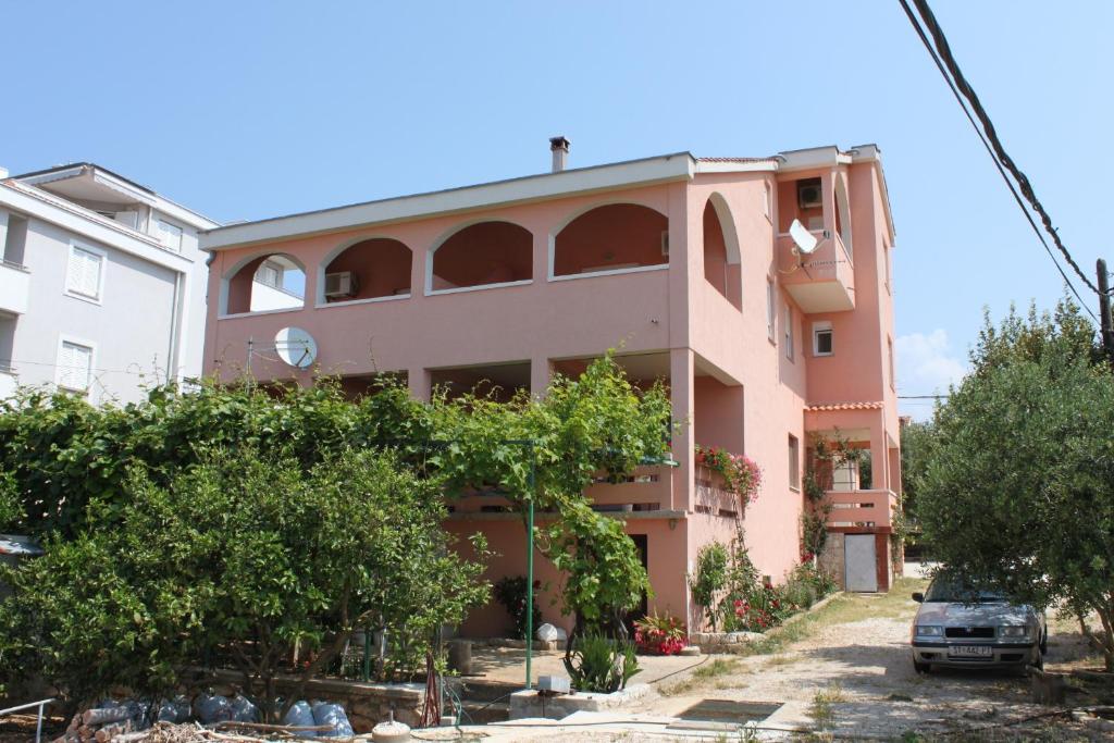 a pink building with trees in front of it at Apartments and rooms with parking space Novalja, Pag - 6341 in Novalja