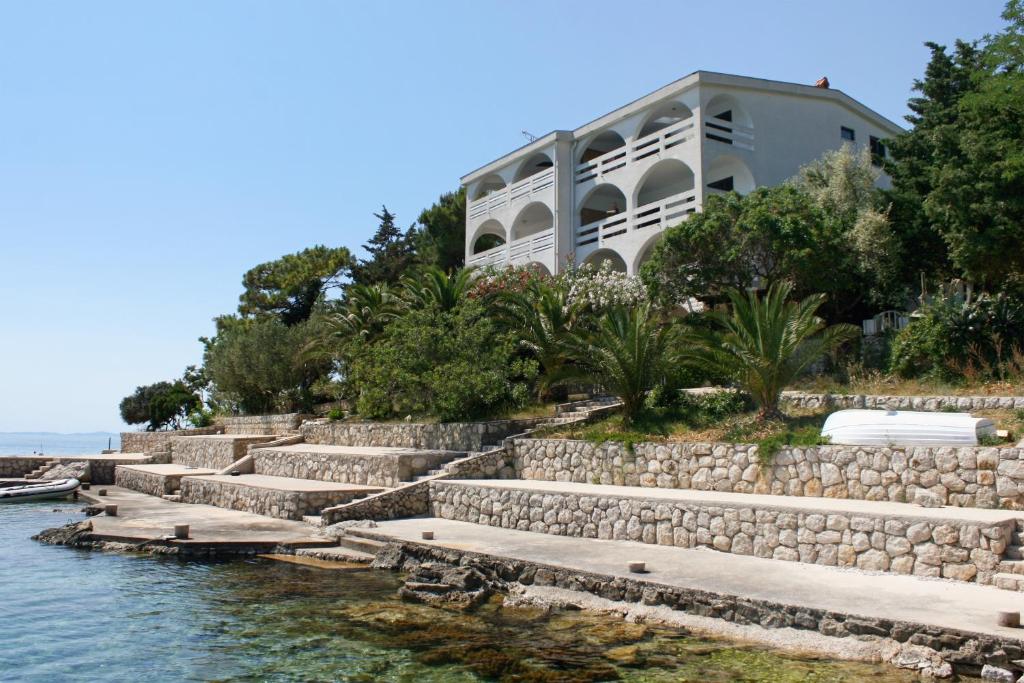 a house on a hill next to the water at Seaside apartments with a swimming pool Potocnica, Pag - 6407 in Borovići