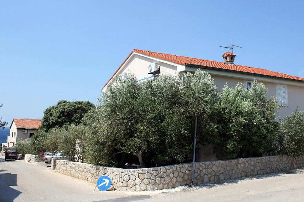 a house with a stone retaining wall next to a street at Apartments by the sea Mandre, Pag - 6373 in Kolan