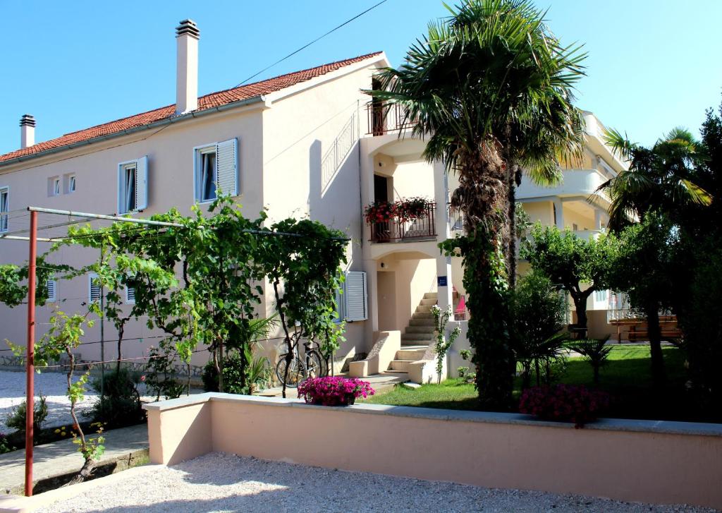 una casa blanca con una palmera delante de ella en Apartments by the sea Sukosan, Zadar - 6402, en Sukošan