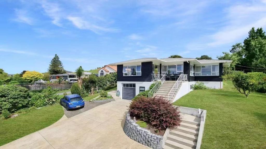 a house with a blue car parked in the driveway at Tranquil mountain peak in Rotorua