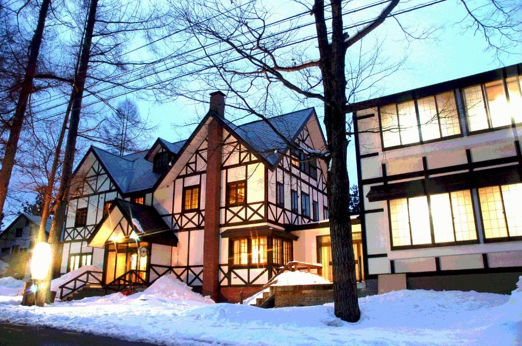 a large house with snow in front of it at Hotel Montblanc Hakuba in Hakuba