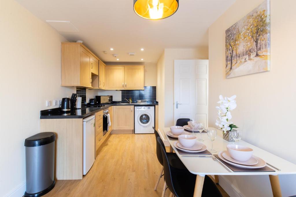 a kitchen with a table with chairs and a dining room at Velvet 1-bedroom penthouse, Clockhouse, Hoddesdon in Hoddesdon