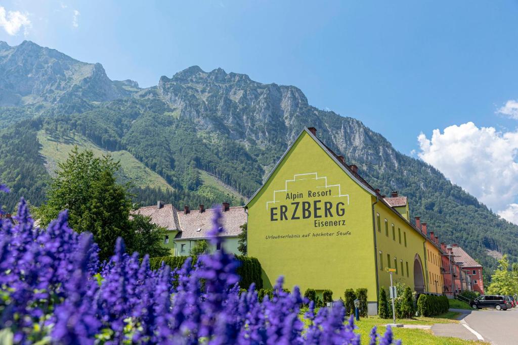 a sign in front of a building with purple flowers at Erzberg Alpin Resort by ALPS RESORTS in Eisenerz