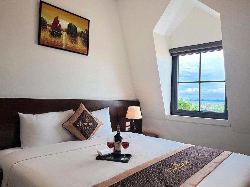 a bedroom with a bed with two glasses of wine at Elysinam Boutique Hotel Ha Long in Ha Long