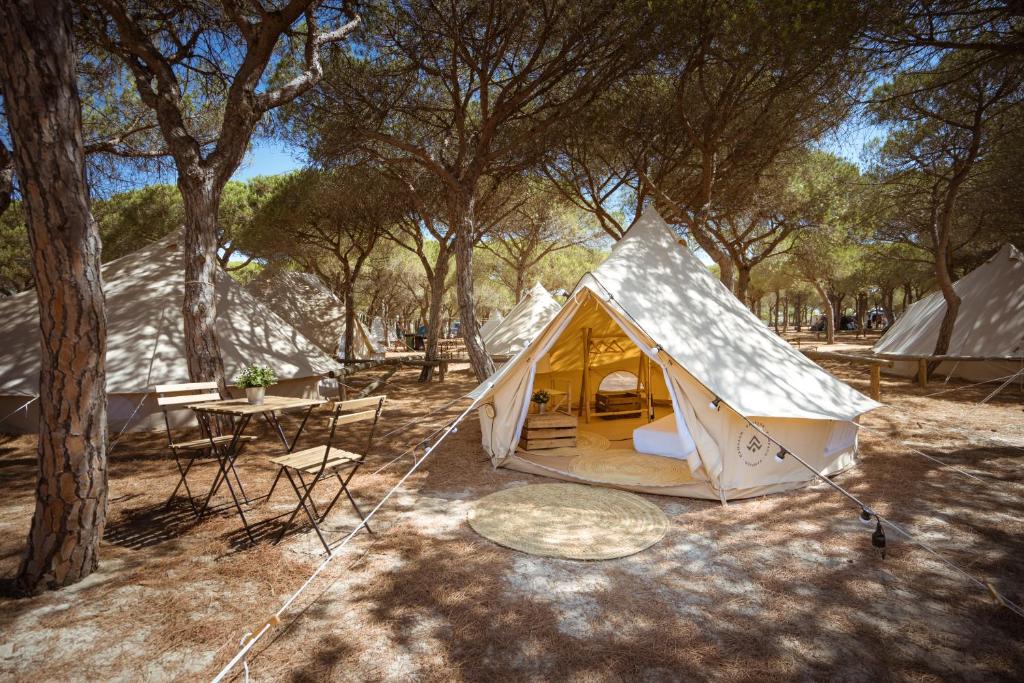 a tent in a field with a table and chairs at Kampaoh Doñana in El Abalario