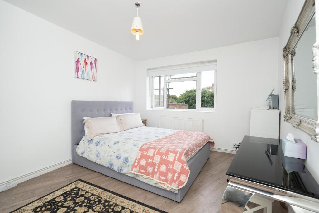 a white bedroom with a bed and a television at Modern 2-bedroom flat near Chelsea in London