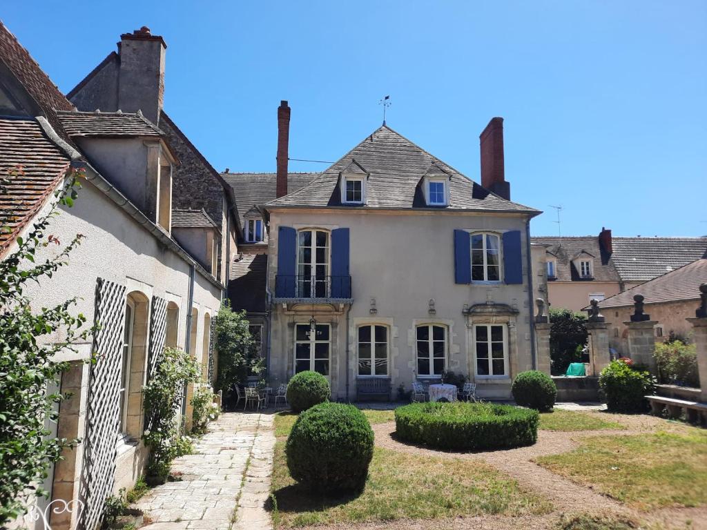 ein altes Haus mit blauen Fenstern und einem Hof in der Unterkunft Maison Zola in Saint-Amand-Montrond
