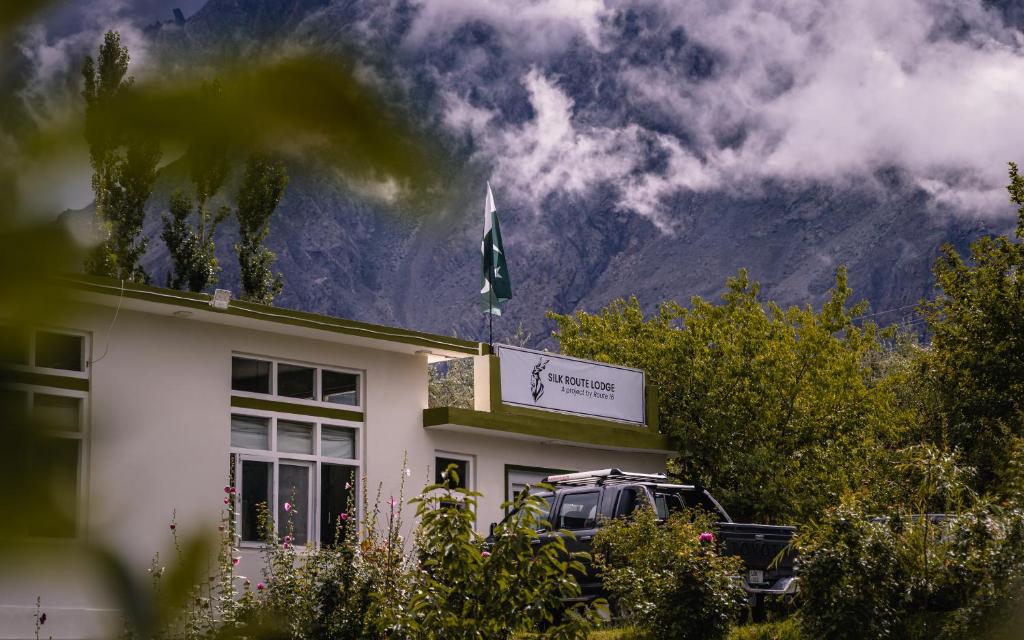 a building with a flag on top of it with a mountain at Silk Route Lodge in Gulmit