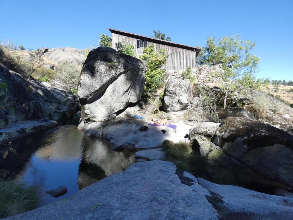 un río con rocas y un edificio al fondo en Salto do Lobo - Montain houses with private river en Penhas da Saúde