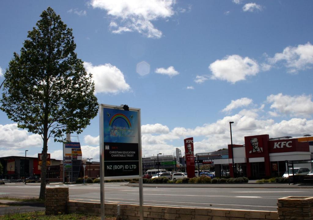 a sign on the side of a street with a tree at Rainbow Motel in Tauranga