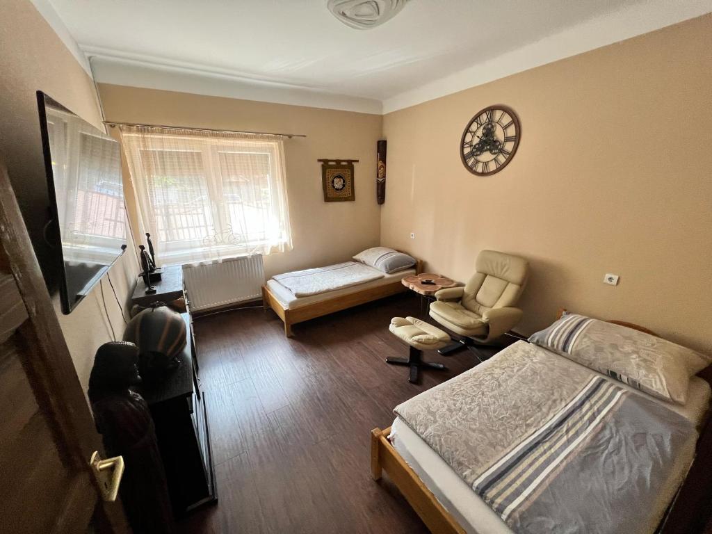 1 dormitorio con cama, sofá y reloj en Fehér galamb apartman, en Gyál