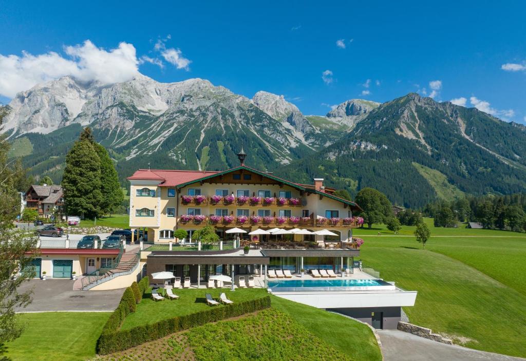 a resort with a pool and mountains in the background at Hotel Ennstalerhof in Ramsau am Dachstein