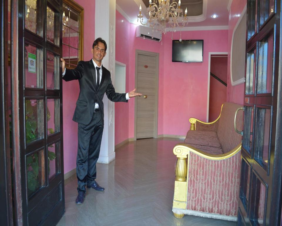 a man in a suit standing in a pink room at Hotel Torvaianica in Torvaianica