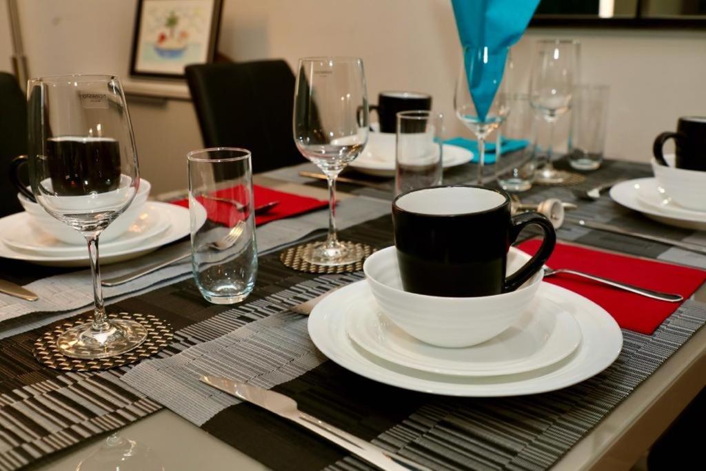 a table with plates and cups and wine glasses at Luxury Modern Belfast City Centre 2 Bed Apartment in Belfast