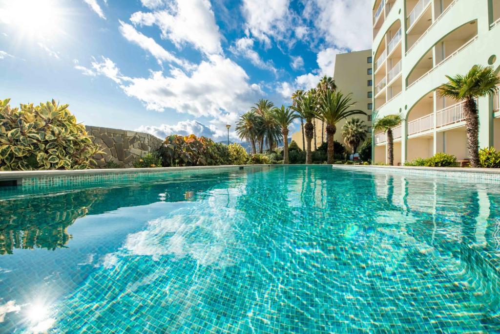 een zwembad met blauw water voor een gebouw bij Pestana Ocean Bay Resort in Funchal