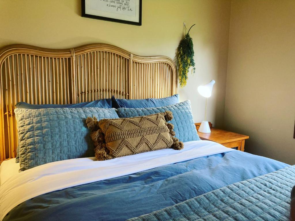 1 cama grande con sábanas azules y cabecero de madera en Red ceder cottage - Great ocean road - Port Campbell en Port Campbell
