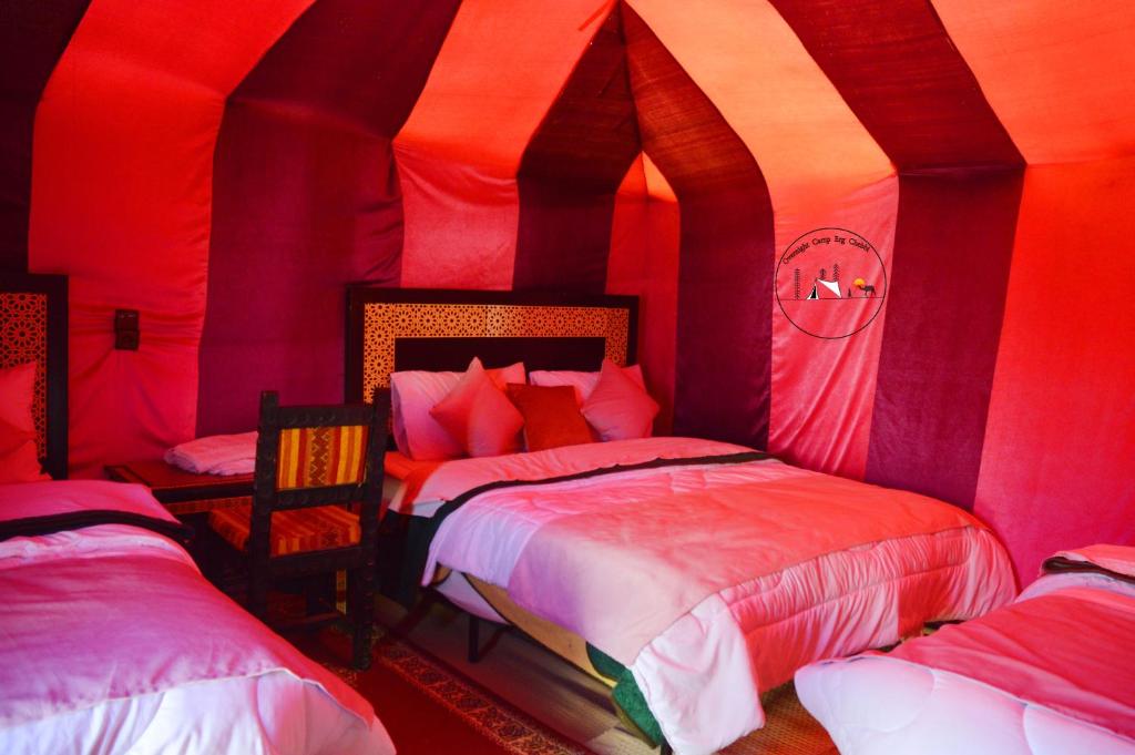 a bedroom with two beds in a room with red lights at Les Roches Desert Camp in Merzouga