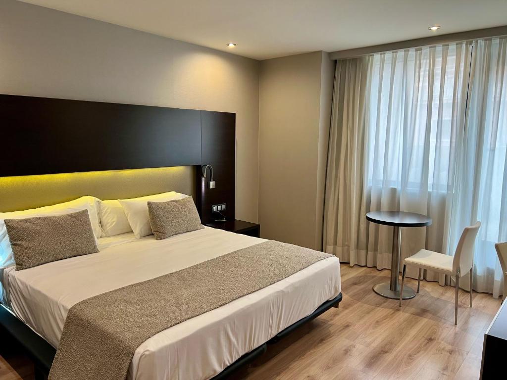 グラナダにあるHotel Tent Granadaの大きなベッドとテーブルが備わるホテルルームです。