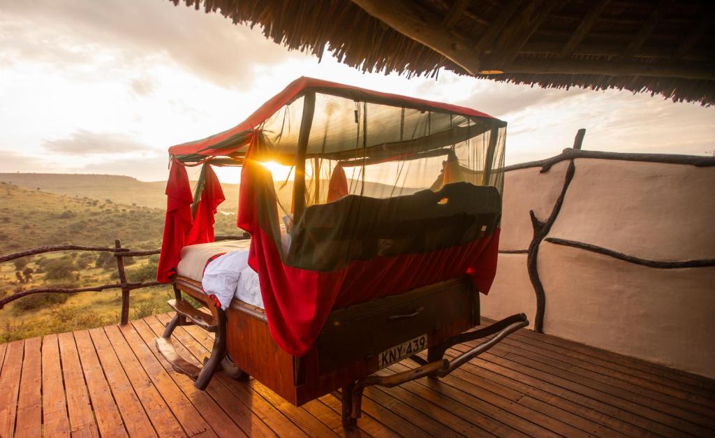 a canopy bed on a deck with a view of the savanna at Loisaba Star Beds in Tura