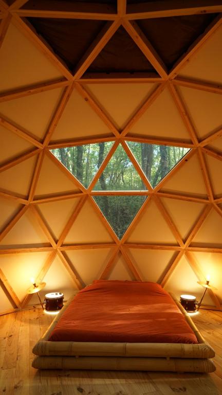ein Schlafzimmer in einem Kuppelzelt mit einem großen Fenster in der Unterkunft Ô Pays Des Bois - Hébergements insolites en pleine nature in Parmilieu