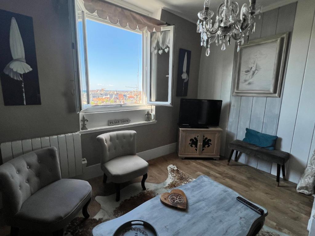 salon ze stołem i krzesłami oraz oknem w obiekcie Location à Trouville sur mer w mieście Trouville-sur-Mer