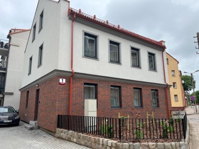 a white and red brick house with a black fence at TOP street ONE Apartments, by Cohost in Klaipėda