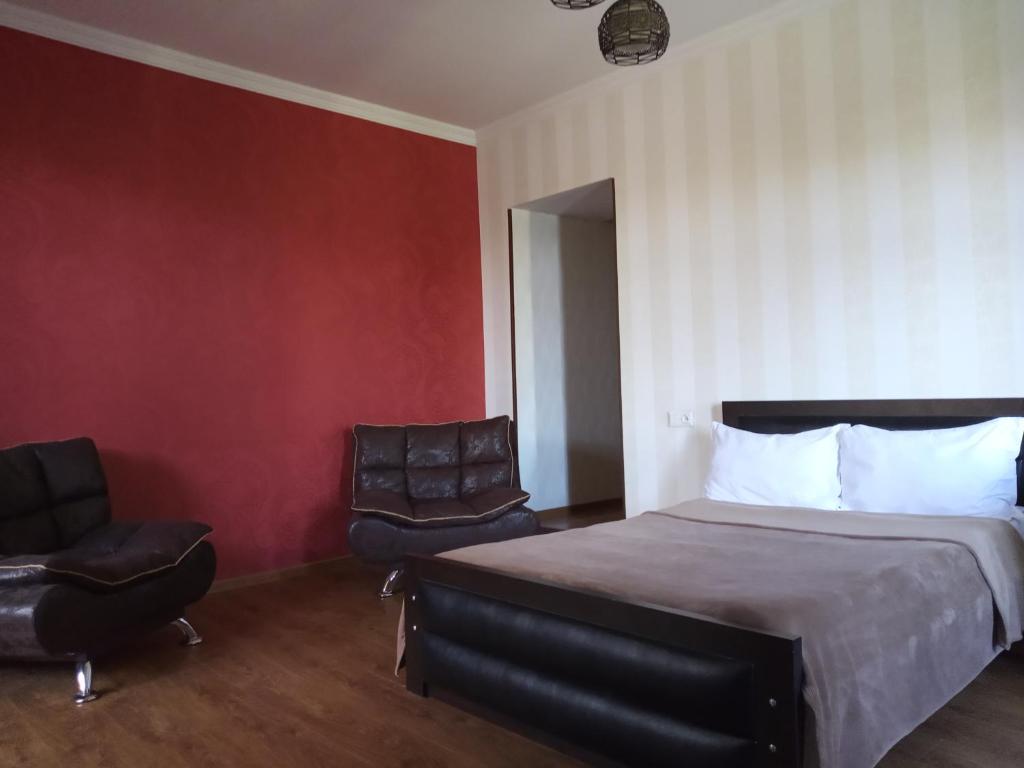 トビリシにあるApartment in the heart of Old Tbilisiのベッド1台と椅子2脚が備わるホテルルームです。