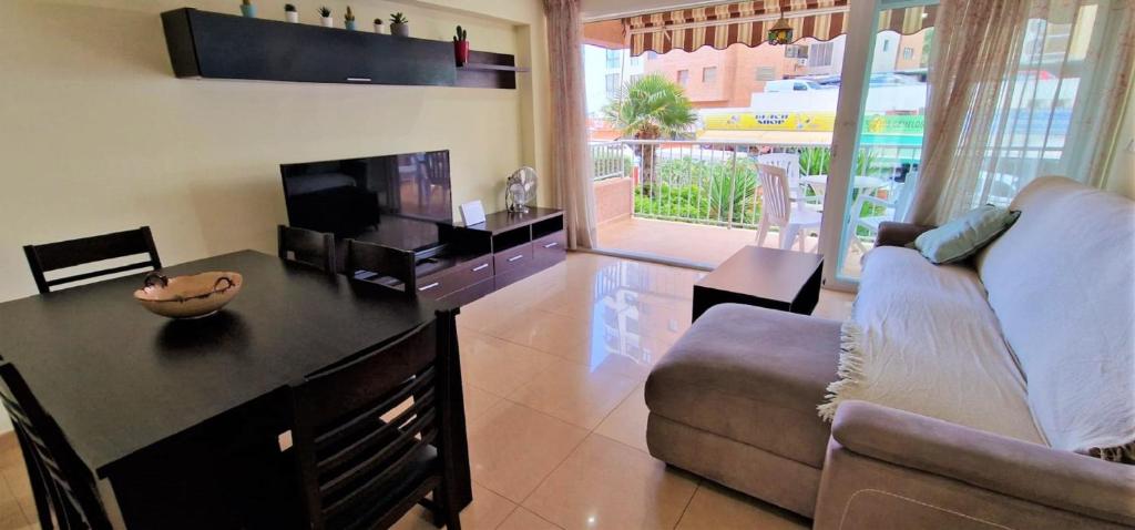 uma sala de estar com um sofá, uma mesa e uma televisão em Los Ranchos, B-1º em Benidorm