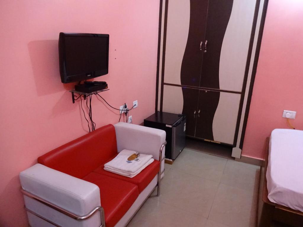 a living room with a red couch and a tv at Hotel Viraat Inn in Gaya