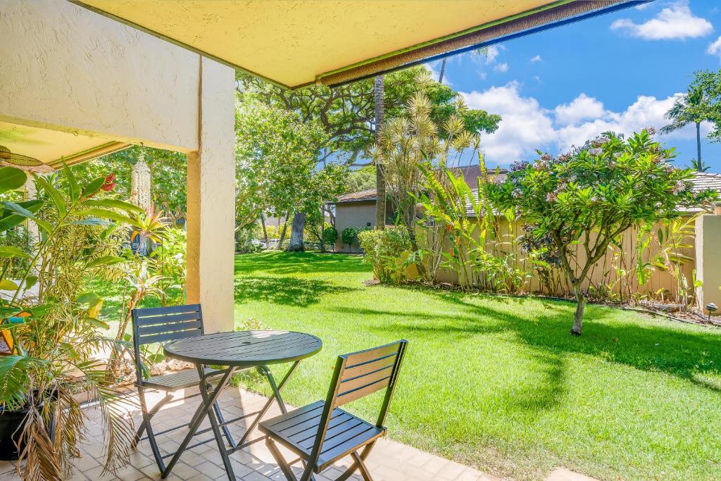 a patio with a table and chairs and a yard at Kihei Gardens Estates G104 in Kihei