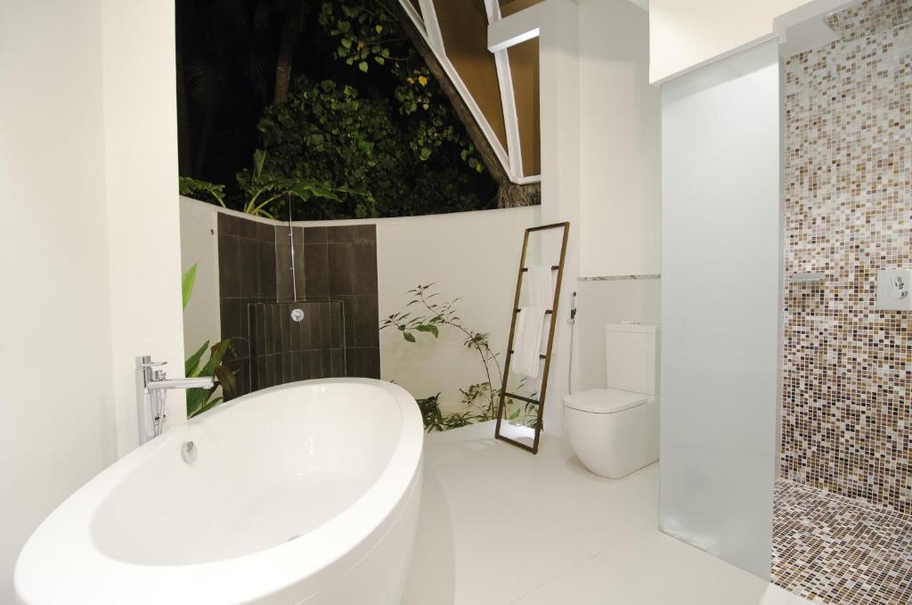 a white bathroom with a tub and a toilet at Kandolhu Maldives in Himandhoo 