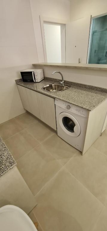uma cozinha com um lavatório e uma máquina de lavar roupa em Apartamentos Tarifa Sun em Tarifa