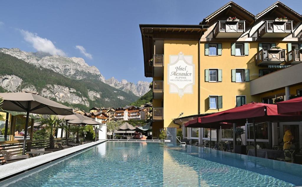 ein Hotel mit einem Pool vor einem Gebäude in der Unterkunft Alexander Hotel Alpine Wellness Dolomites in Molveno