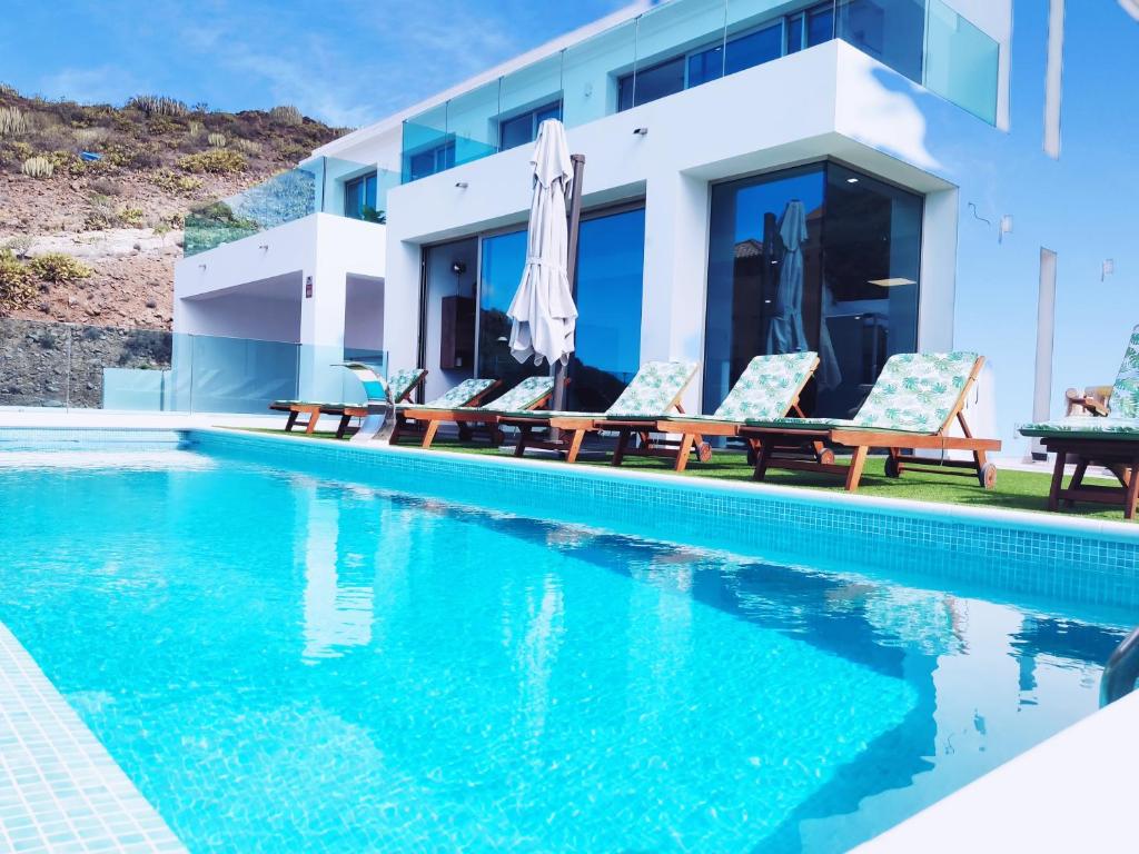 eine Villa mit einem Pool mit Chaiselongue in der Unterkunft Elegante y moderna Villa Miami in Adeje