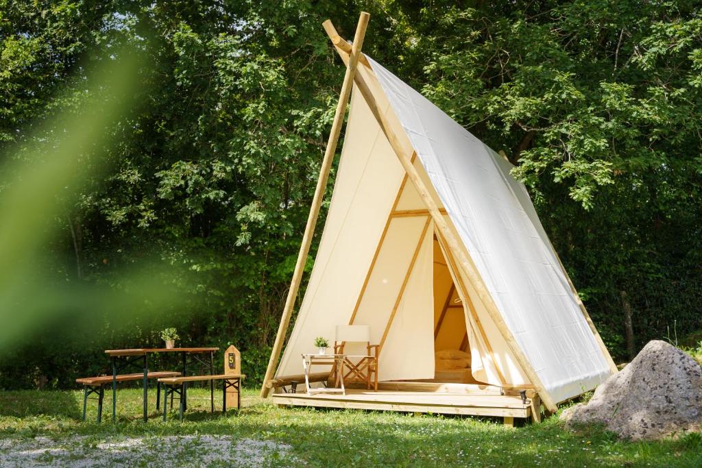 a white teepee tent with a table and chairs at Kampaoh Ruiloba in Liandres