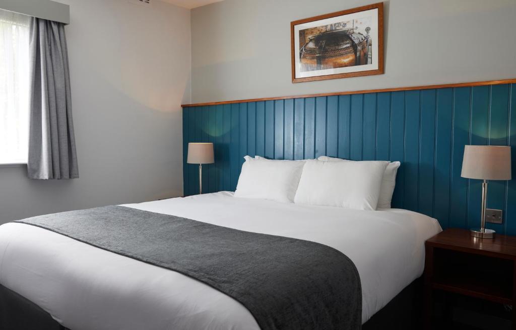 um quarto com uma cama grande e uma parede azul em The Longshoot em Nuneaton