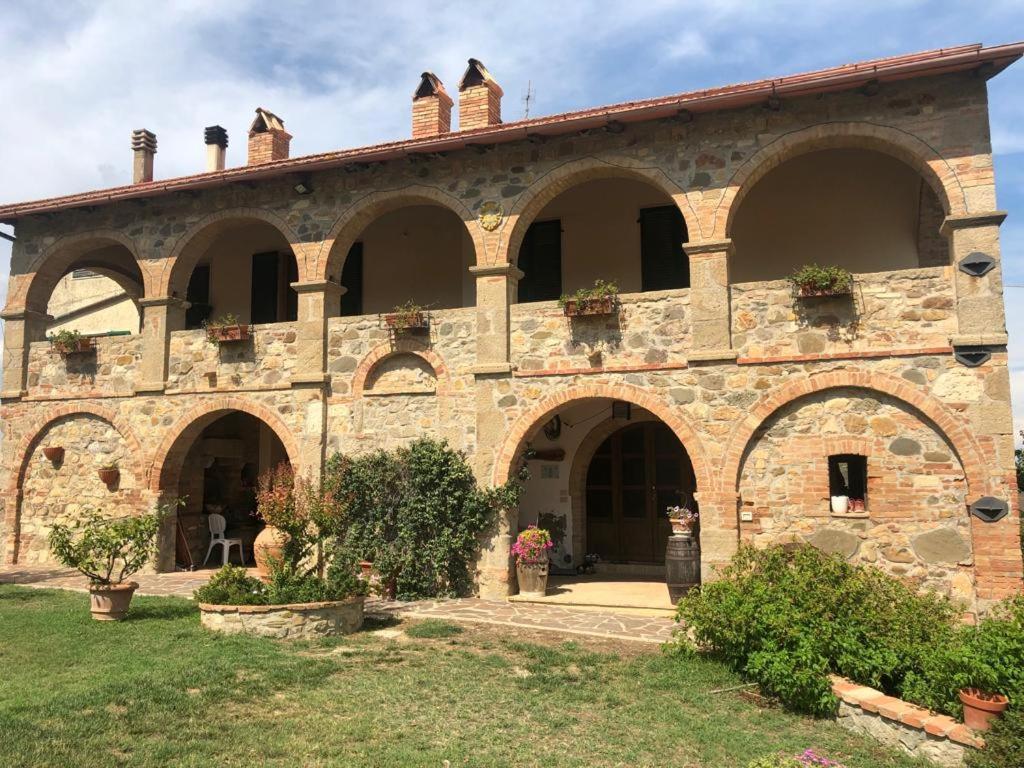 a large brick building with arches and plants on it at Agriturismo Il Pozzo in Castiglione dʼOrcia