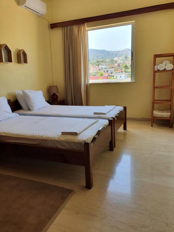 a bedroom with two beds and a large window at Sunny House in Vathí