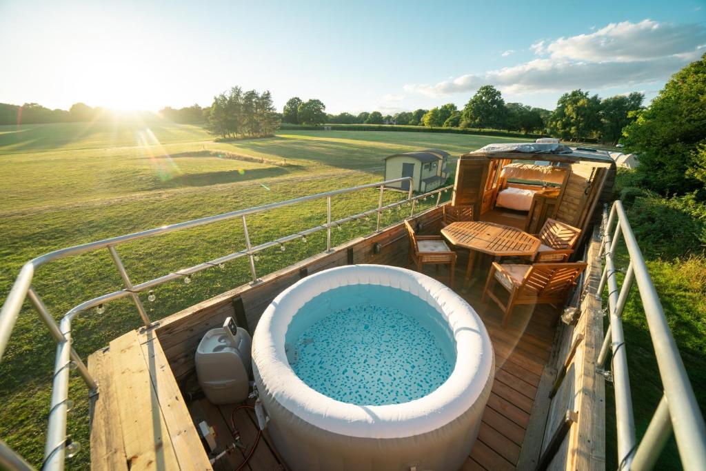 a bath tub sitting on a deck next to a field at Delightful 2 Bed Double Decker Bus with Hot Tub in Uckfield