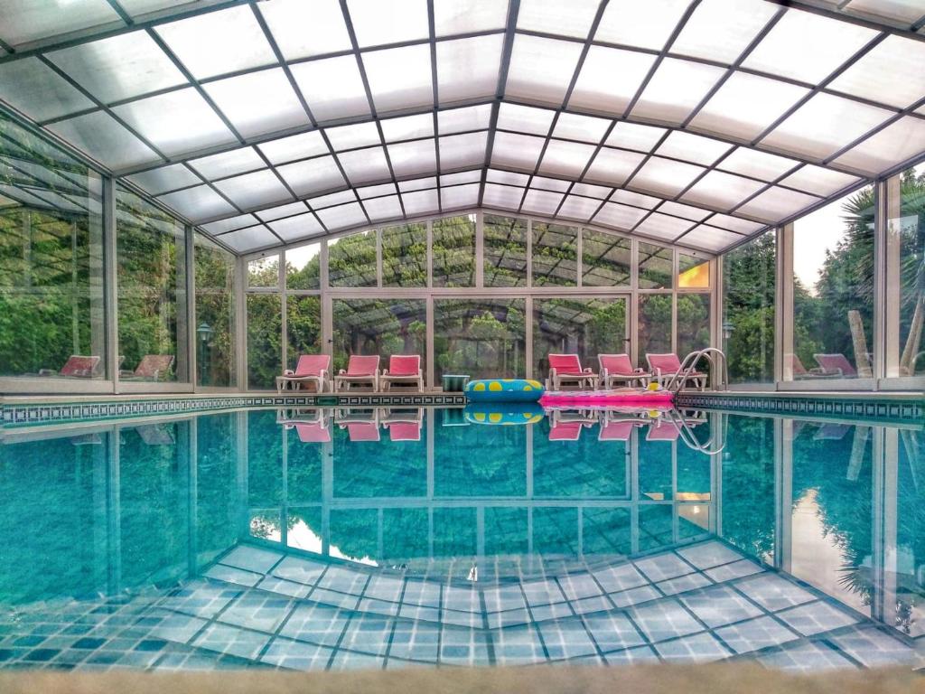 an indoor swimming pool with chairs and a large glass ceiling at Our Lady of Mercy Villa in Ermesinde