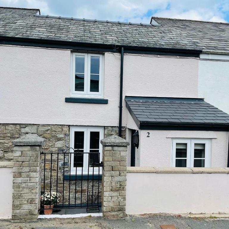 a white house with a black roof at River Cottage in Abercraf