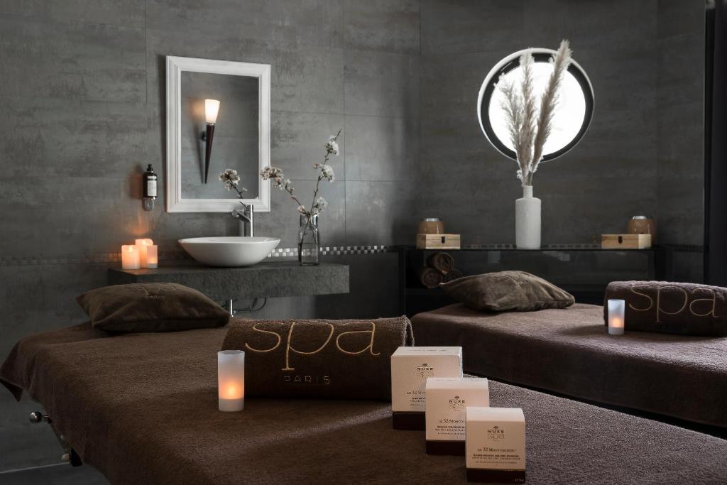 two beds in a room with candles and a sink at Golf Hôtel de Valescure &amp; Spa NUXE in Saint-Raphaël