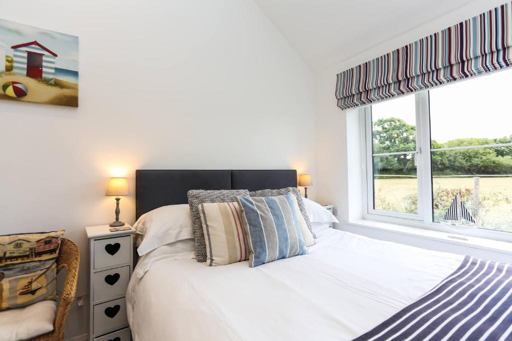 a bedroom with a white bed and a window at Linden House in West Wittering