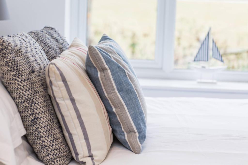 a group of pillows sitting on a couch with a window at Linden House in West Wittering