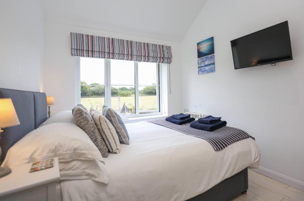a bedroom with a bed with a tv on the wall at Linden House in West Wittering
