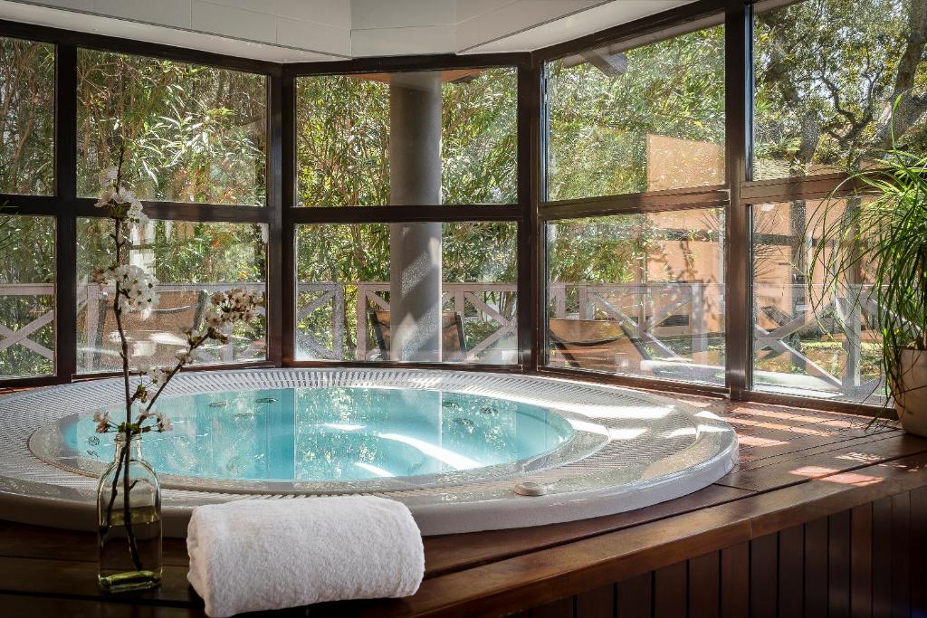 a jacuzzi tub in a room with windows at Golf Hôtel de Valescure &amp; Spa NUXE in Saint-Raphaël